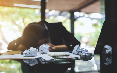 Businesswoman get stressed with screwed up papers and laptop on table while having a problem at...