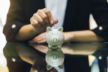 A woman putting coins into piggy bank for saving money concept