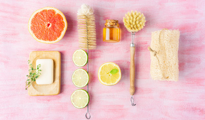 Bottle and dish brush, ingredients for homemade cleaning soap, some citrus and herbs near.  Zero waste and natural ingredients home cleaning concept. Top view, layout. 