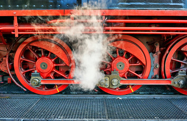 Fototapeta na wymiar Detail of the wheels of a steam locomotive with steam.