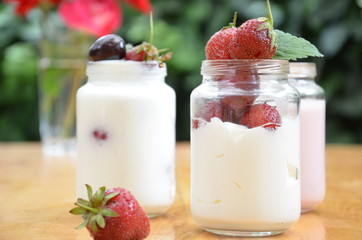 Healthy breakfast home made pudding or yogurt or granola, strawberries, cherry, berry,  yogurt in a bowl. Vegetarian concept food. pudding or cocktail on of green foliage