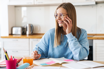 Image of woman talking on cellphone while studying with exercise books