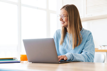 Image of cheerful charming woman smiling while working with laptop