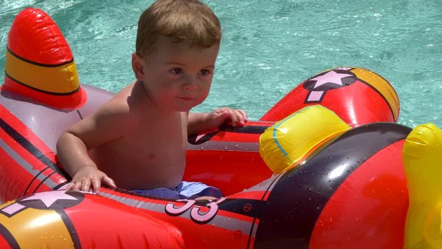 Toddler in floatable airplane in pool. Close up, high angle