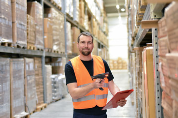 Warehouse worker scans parcels in the warehouse of a forwarding company for transport - obrazy, fototapety, plakaty