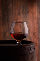 Glass of cognac on the old wooden barrel