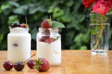 Healthy breakfast home made pudding or yogurt or granola, strawberries, cherry, berry,  yogurt in a bowl. Vegetarian concept food. pudding or cocktail on of green foliage