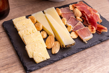 Small cheese platter with Serrano ham and Iberian loin. Spanish traditional snack.