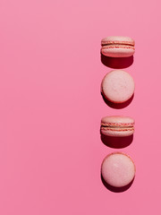 Pink macarons with copy space. Row of perfect french macarons or macaroons on pink background. Top view or flat lay. Hard light