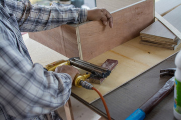 carpenter use air-gun for make new furniture