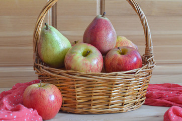 Fresh fruit on a wooden background. Straw basket with apples and pears. Autumn harvest in season....