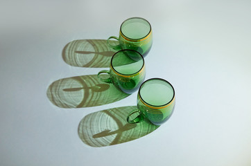 three green glass cups with handles stand in a row
