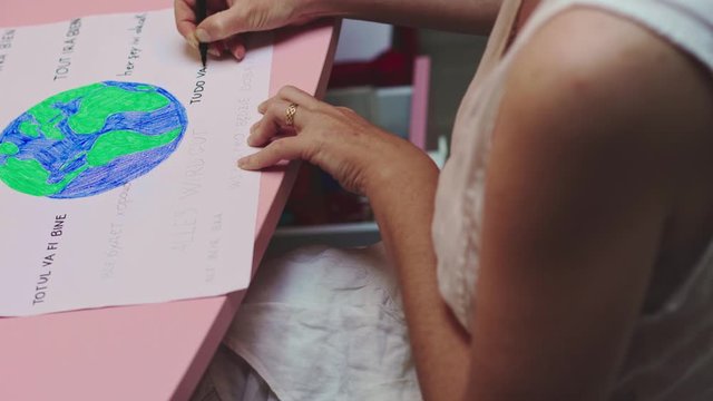 Zoom out on woman writing all will be ok in different languages of the world