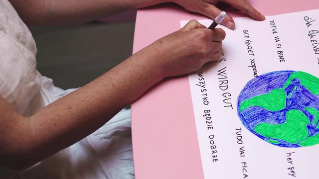 Woman in self-isolation writes all will be ok in many idioms as motto against COVID-19