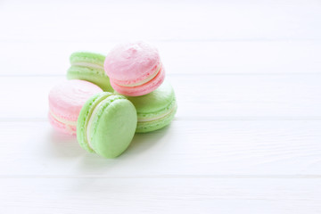 Sweet ?olorful pink and green macaroons. A french sweet delicacy. White wooden board, empty space