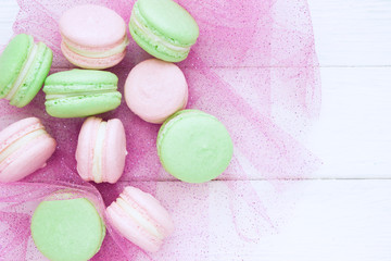 Sweet ?olorful pink and green macaroons. A french sweet delicacy. White wooden board, empty space