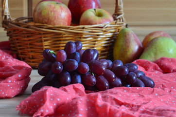 Autumn seasonal harvest and fresh fruit on a wooden background and a red handkerchief. Grapes, pears and apples. Healthy food and snacks for a slim figure