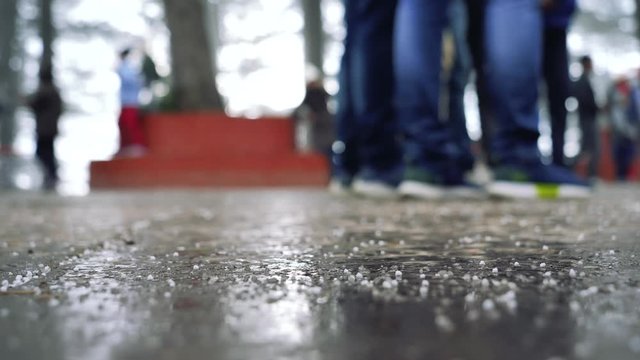 Snowfall on the wet floor with footsteps of indistinct people walking and kids playing.