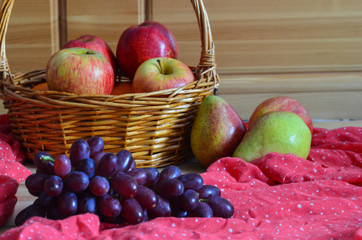 Autumn seasonal harvest and fresh fruit on a wooden background and a red handkerchief. Grapes,...