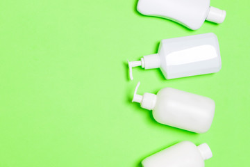 Set of White Cosmetic containers isolated on green background, top view with copy space. Group of plastic bodycare bottle containers with empty space for you design