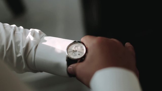 man in business suit puts on expensive watch, top view. groom's details. The groom puts on his watch. closeup