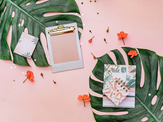 Feminine creative design workspace. Notebook, tropical leaves on pink background, blogger concept