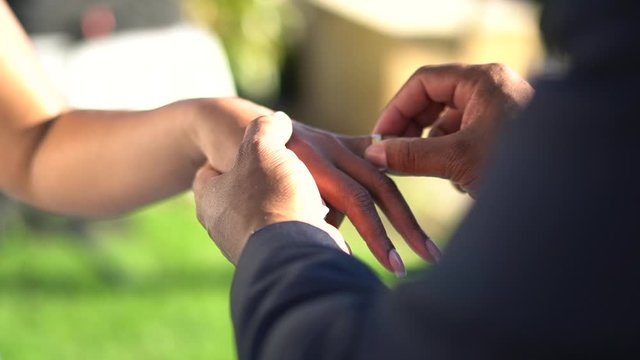 Slow motion of a black man putting a wedding ring on a bridal hand