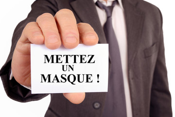 Homme tenant une carte sur laquelle est écrit mettez un masque