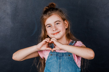 Portrait of a fun cute charming cute little girl showing various gestures. On a slate background.