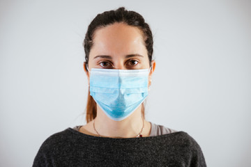 Portrait of a beautiful young woman with a medical mask of protection from the Coronavirus, Covid-19 - Millennial protects herself from the infection by wearing personal protection tools