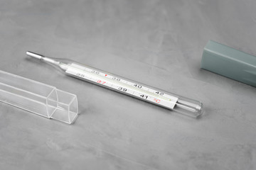 Mercury thermometer on a gray background near the case.