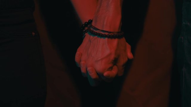 Man and woman holding hands in a dark room