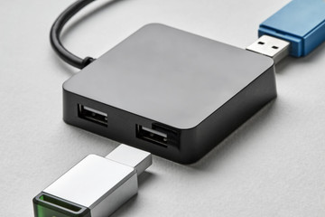 Black portable USB hub for four connections with usb flash drives on a white background. Bus povered. Closeup, selective focus