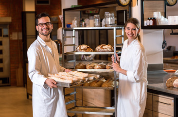 Portrait of two young bakers standing at bakery.