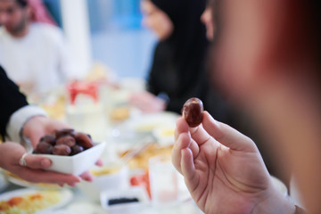 Obraz na płótnie Canvas Muslim family having Iftar dinner eating dates to break feast