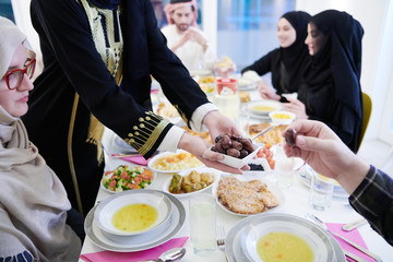 Muslim family having Iftar dinner eating dates to break feast