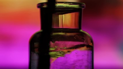 Wooden stick stirring two liquid substances in chemistry lab jar illuminated with neon lights from behind creating whirlpool. - Powered by Adobe