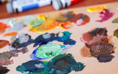 Close up oil painting process. Oil paints palette. Oil painting tools on the wooden table. Painter work place.