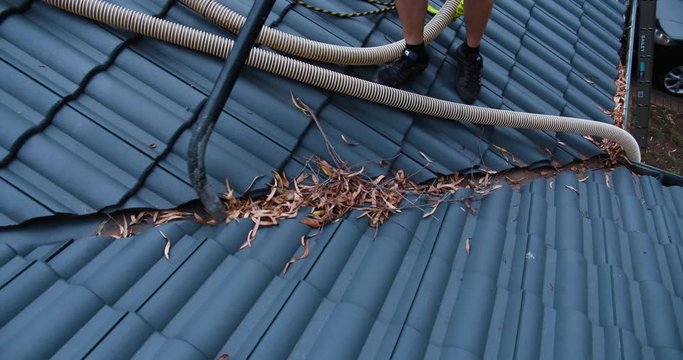 Man cleaning dead leaves out of roof gutters
