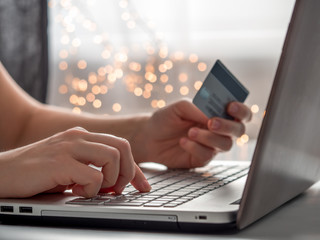 Cristmas online shopping soncept. Close-up woman's hands holding credit card and inputting card...