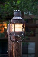 Retro lamp outdoors. Traditional street light, rusty and wooden outdoor decor. Vintage lighting with retro concept. Decorative metal object in a street.