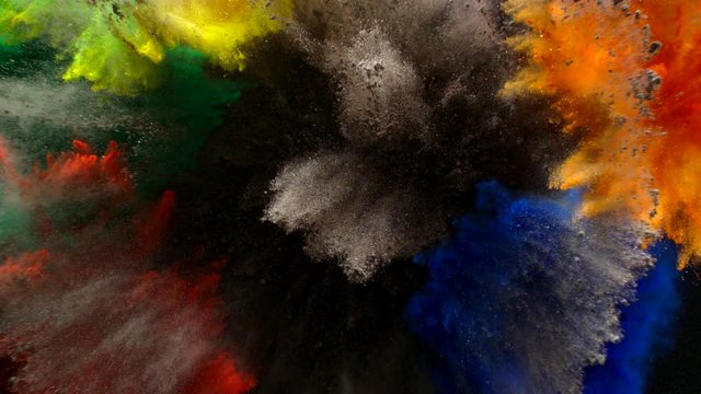 In real slow motion, separated clumps of yellow, purple, orange, blue, red, green and black powder explodes simultaneously towards the camera like fireworks. Top Shot