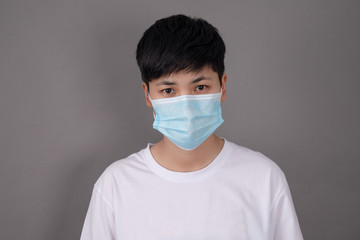 Portrait of a person in a white T-shirt wearing a protective mask on a gray background