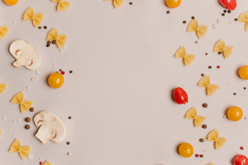 Uncooked pasta, tomatoes, mushroom slices and spices on a beige background, top view, close-up. Cooking, fettuccine, yellow and red cherries.