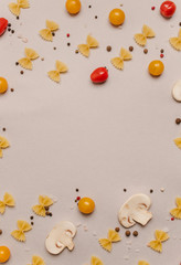 Uncooked pasta, tomatoes, mushroom slices and spices on a beige background, top view, close-up. Cooking, fettuccine, yellow and red cherries.