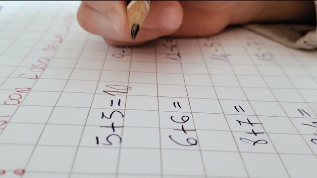 Close up of primary school kid doing math homework on excercise book,home family