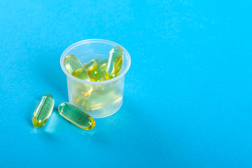Transparent capsules in a measuring cup. Dosage of drugs. Nutritional supplements. Vitamins