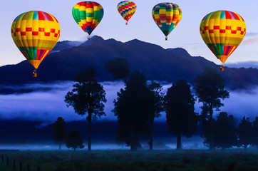 Colorful Hot air balloon flying over  the sky at mountains, trees and night mist