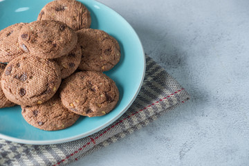 Delicious crunchy homemade chocolate cookies on a plate with cloth napkin, marble table with dark background. Rustic concept