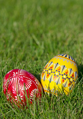 Zwei handbemalte Ostereier liegen im Gras, Hochformat